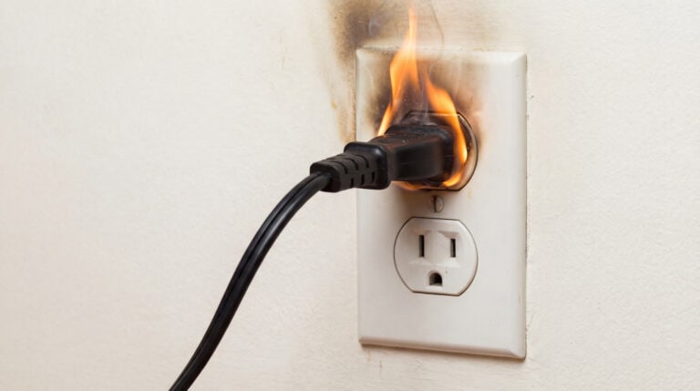 Power cord caught fire in an electrical outlet, posing fire risk.