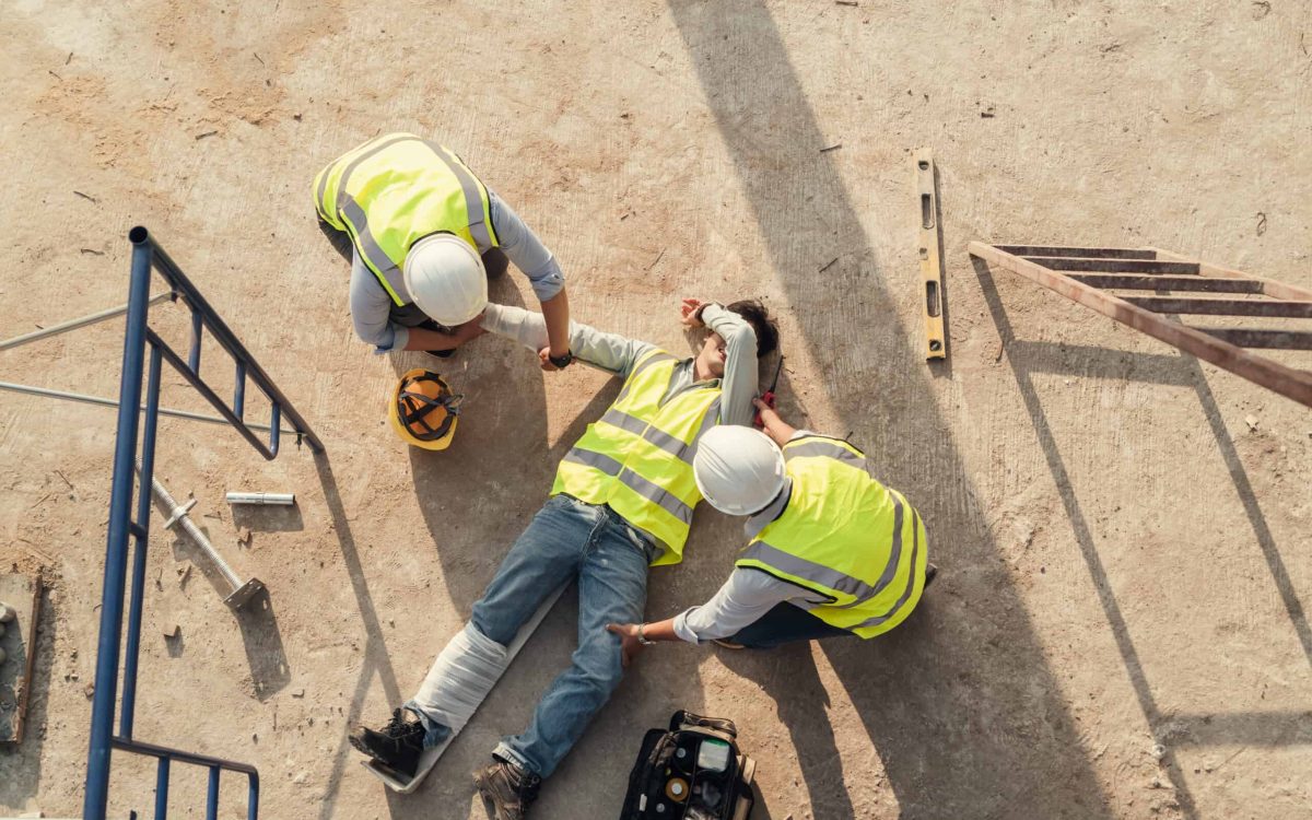 Workers assisting injured colleague on construction site.