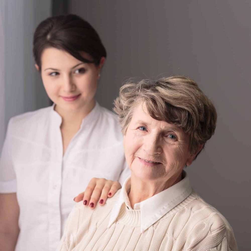 Elderly woman and caregiver discussing dignity and privacy training.