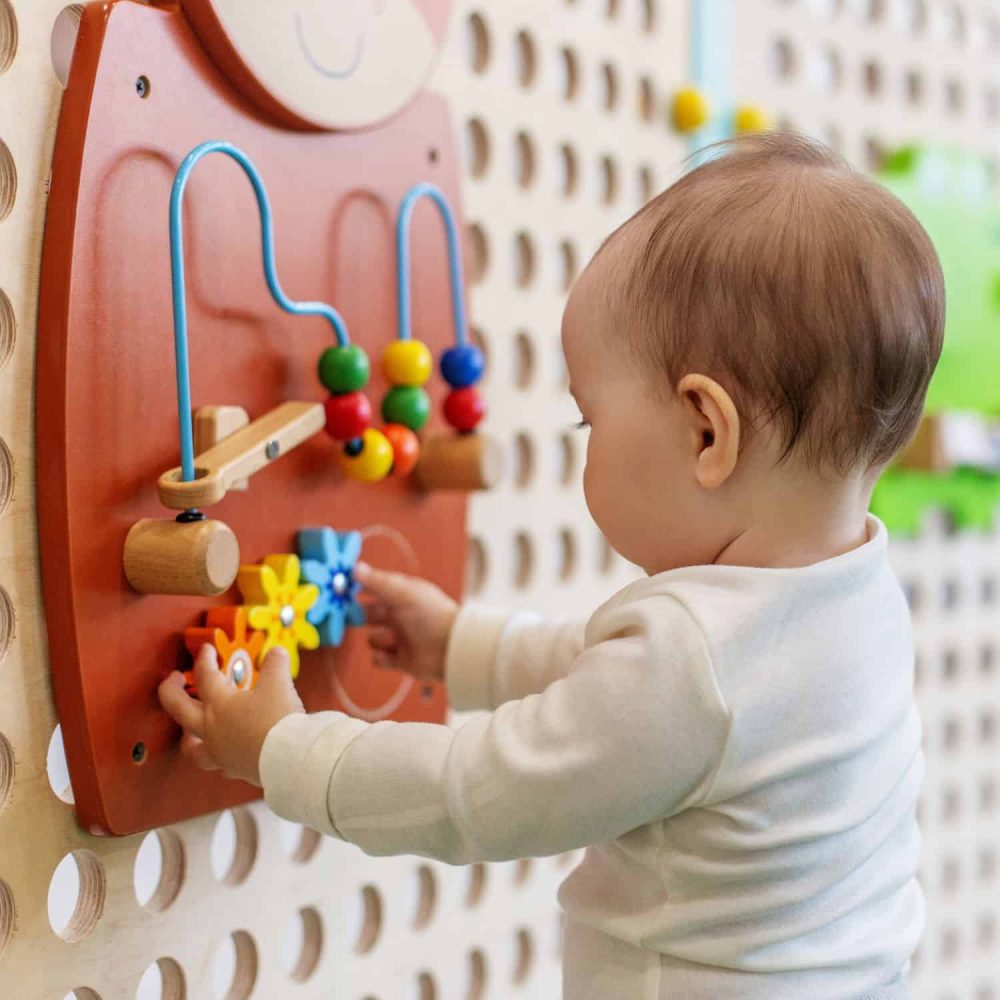 Young child playing with educational bead maze toy in a classroom.