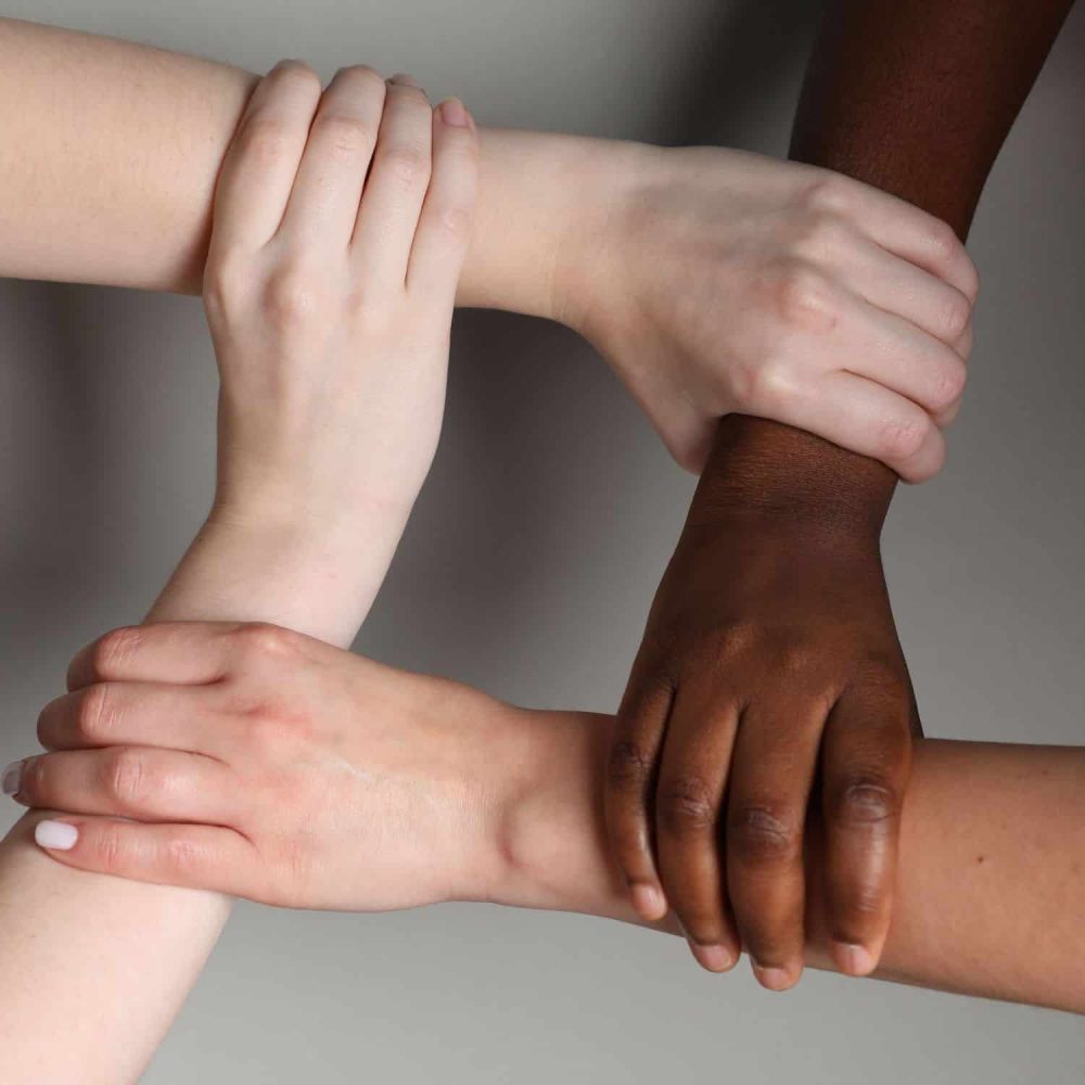 Diverse hands joined together symbolising unity and inclusion.