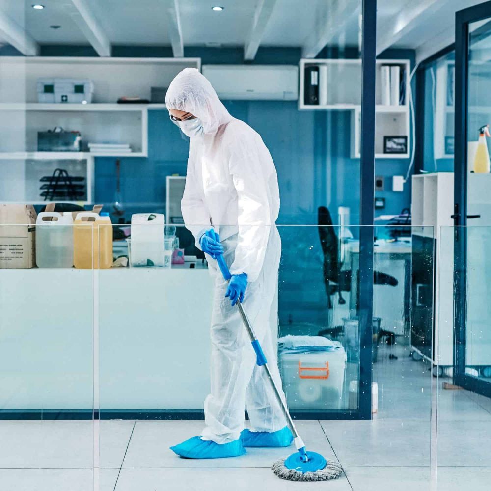 Person in protective gear cleaning laboratory floor for infection control.