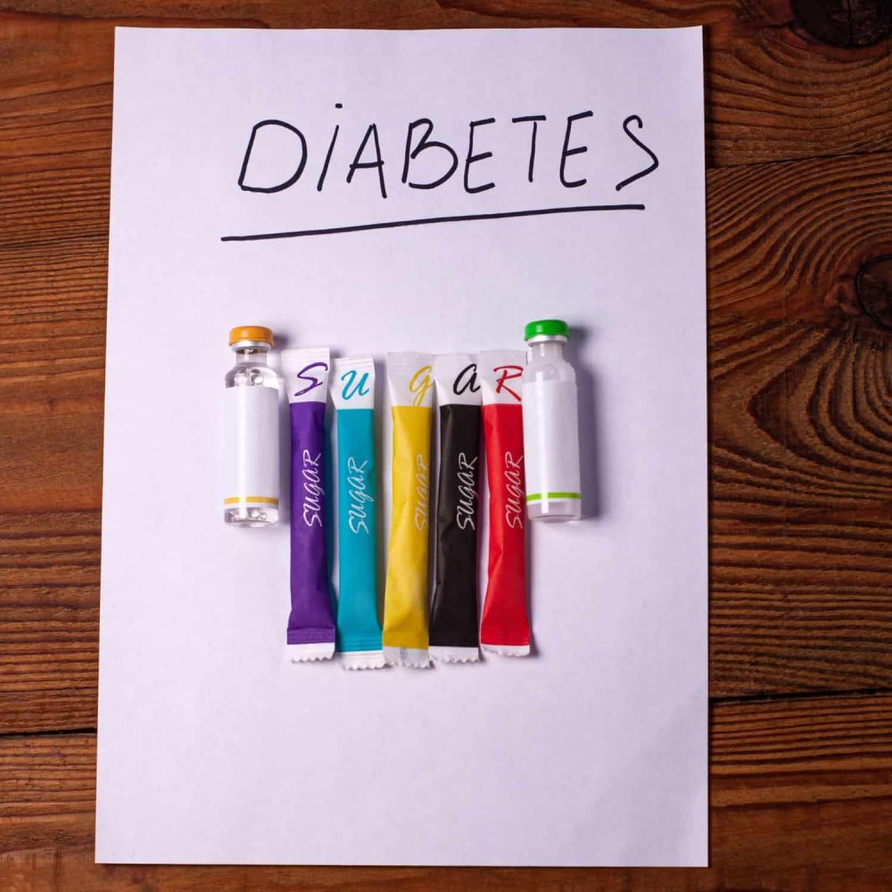Colorful insulin syringes on paper with 'Diabetes' written above.