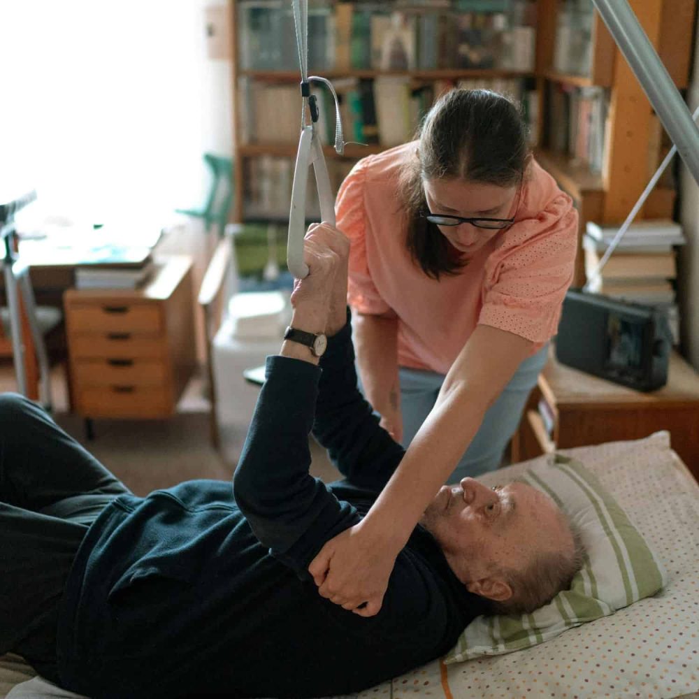 Caregiver assisting a patient with physical therapy exercises.