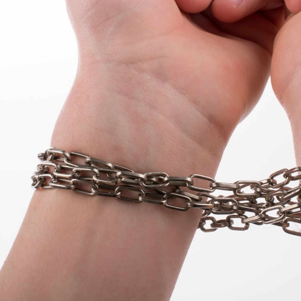 A person's wrist with metal chains as a symbol of restraint or oppression.