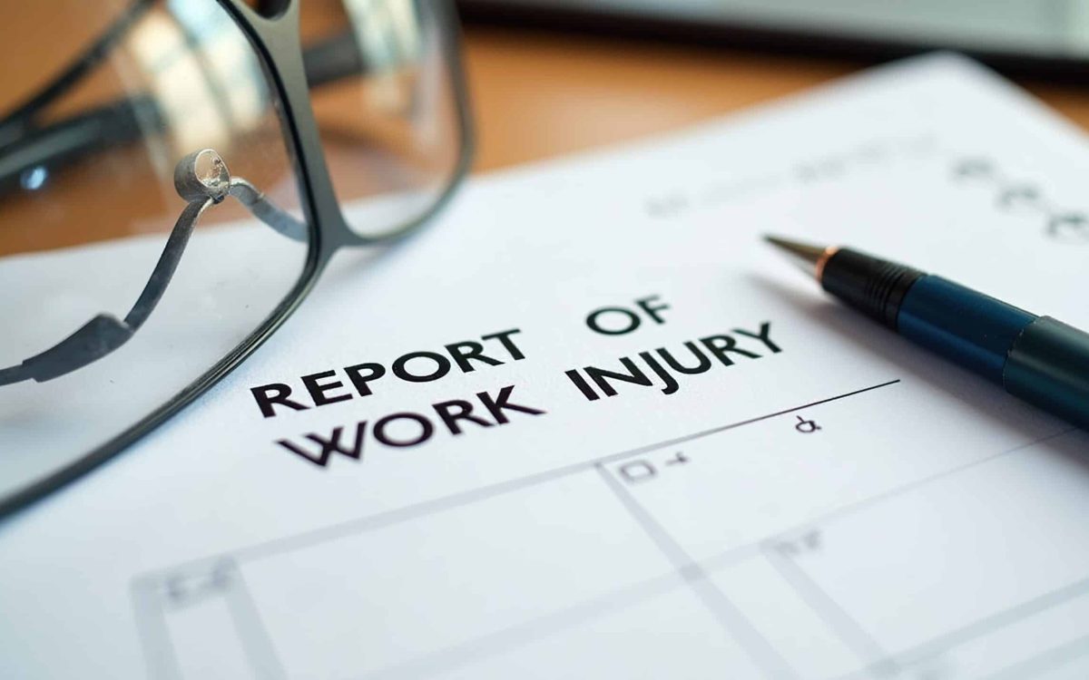 Work injury report form with glasses and pen on a desk.