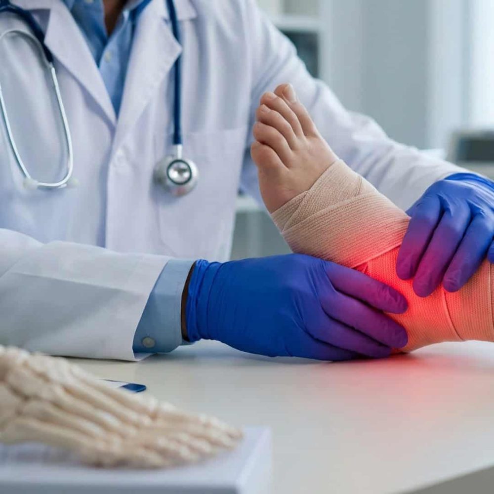 Doctor examining and treating ankle injury with red highlight on ankle.