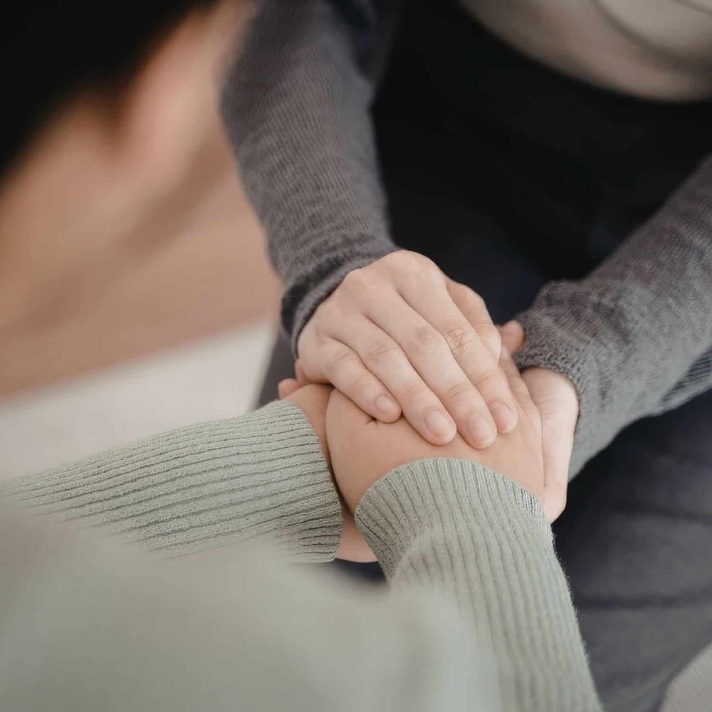Two adults holding hands in a supportive gesture for safeguarding training.