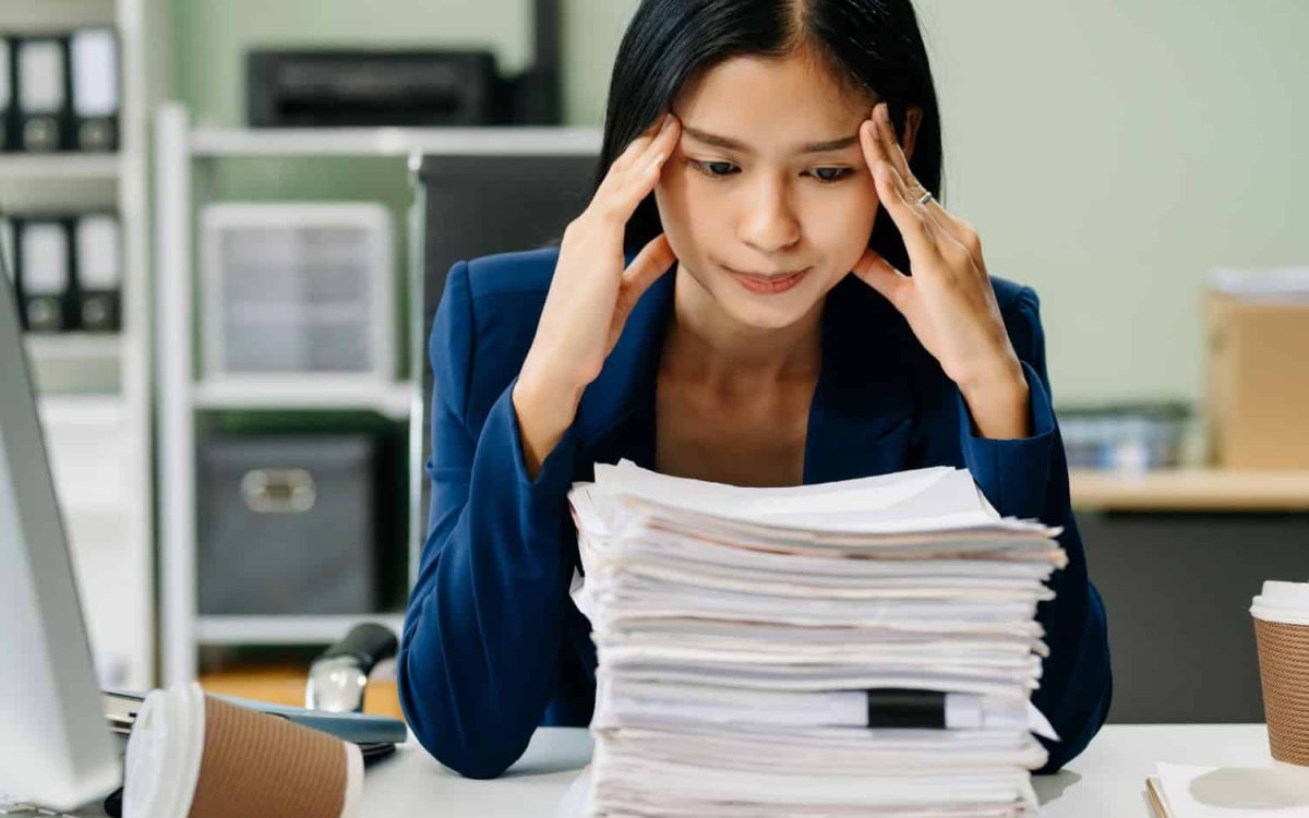 Overwhelmed woman with stress at work, managing workload.