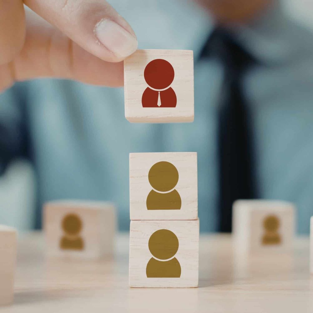 Person stacking wooden blocks with icons representing team members.